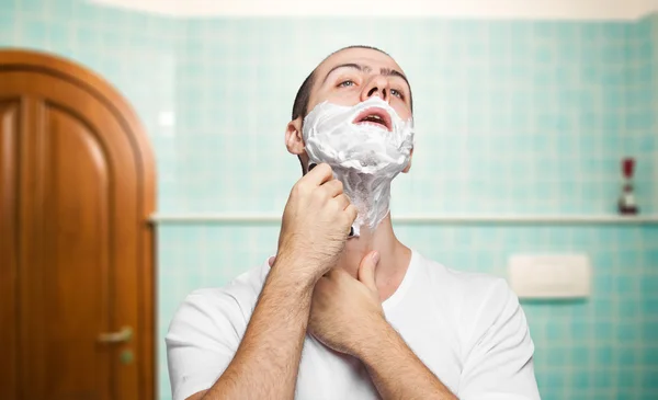 Man using disposable razor to shave beard off