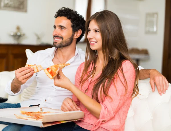 Casal assistindo televisão enquanto come pizza — Fotografia de Stock