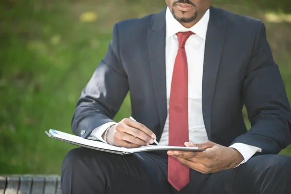 Geschäftsmann schreibt Notizen im Sitzen auf Bank — Stockfoto