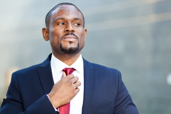 Negro hombre de negocios ajustando su mirada — Foto de Stock