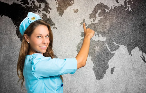 Hospedeira sorridente na frente de um mapa do mundo — Fotografia de Stock