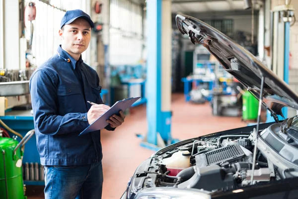 Mechanic schrijven op document in garage — Stockfoto