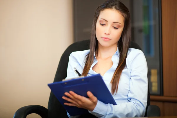 Businesswoman writing on clipboard — Stock Photo, Image