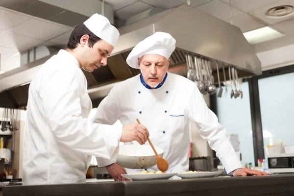 Шеф-кухар спостерігає за своїм помічником, прикрашаючи тарілку — стокове фото