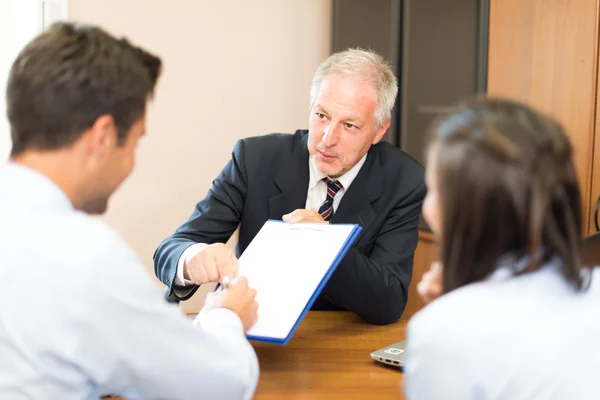 Hombre de negocios mostrando un documento para firmar a la pareja — Foto de Stock