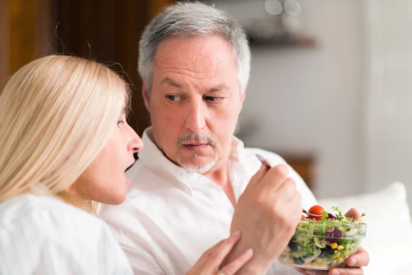 Casal maduro falando e comendo uma salada — Fotografia de Stock