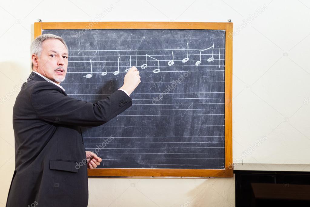 Music teacher writing on blackboard