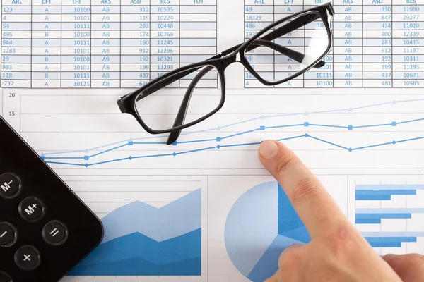 Calculadora, óculos e gráficos financeiros — Fotografia de Stock