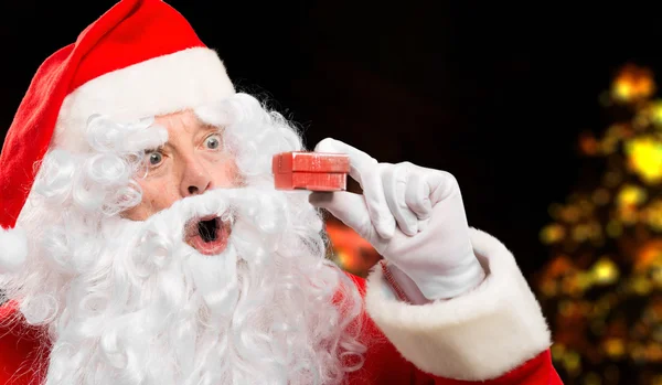 Weihnachtsmann schaut überrascht auf Geschenk — Stockfoto