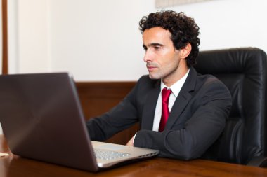 Ofiste dizüstü bilgisayar kullanan bir iş adamı