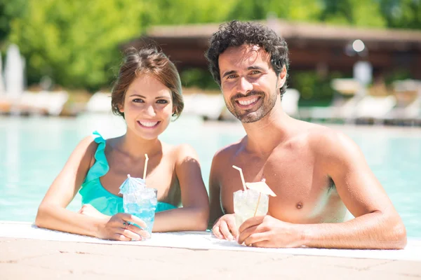 Casal desfrutando de um coquetel na beira da piscina — Fotografia de Stock