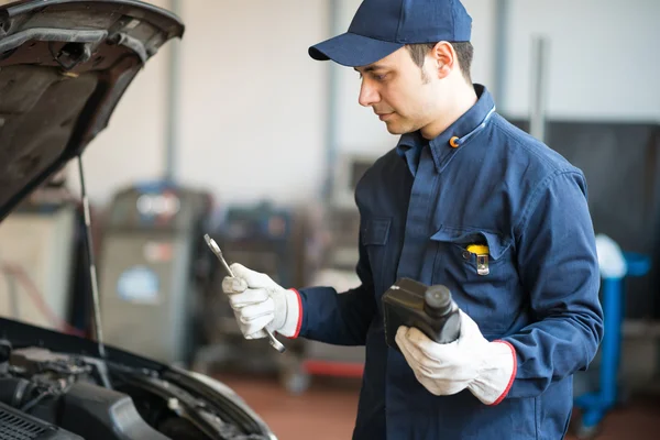 Auto mecánico sosteniendo una jarra de aceite de motor — Foto de Stock