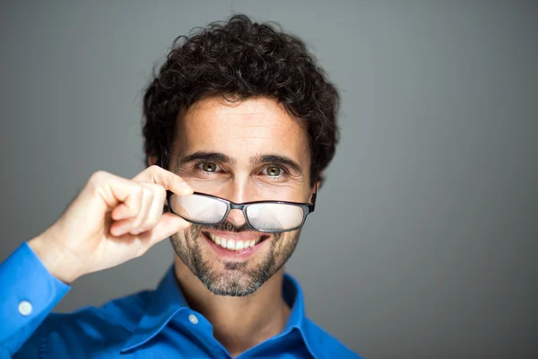 Atractivo joven sosteniendo gafas — Foto de Stock