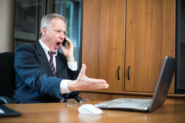 Злой бизнесмен кричит на телефон — стоковое фото