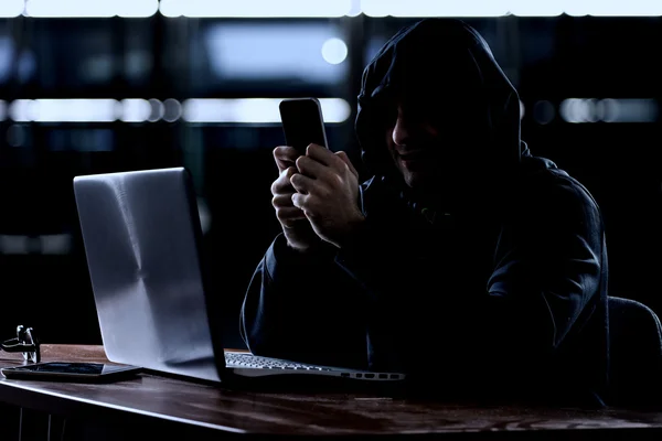 Хакер с помощью смартфона — стоковое фото