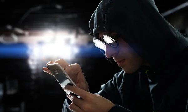 Хакер держит телефон — стоковое фото