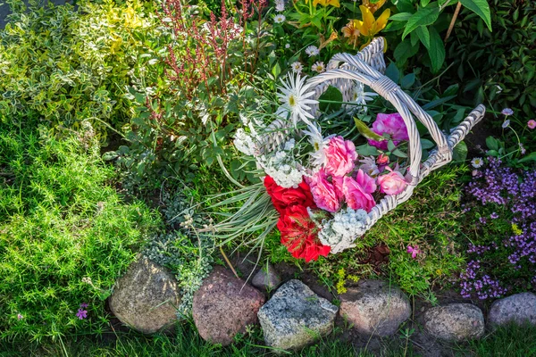 Beautiful flowers in basket in garden — Stock Photo, Image