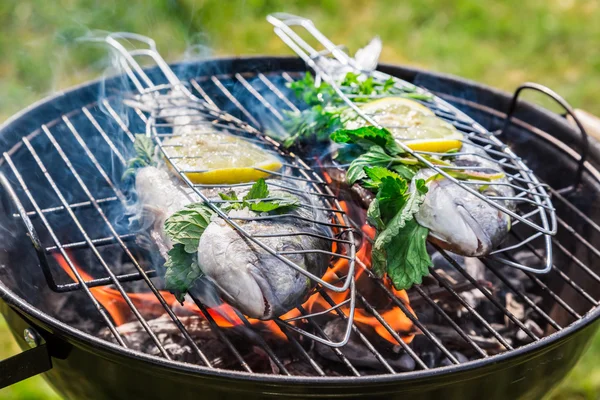 Asar pescado sabroso a la parrilla con hierbas y limón — Foto de Stock