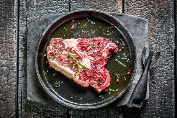 Fresh piece of red meat with rosemary and pepper ready for grilling — Stock Photo, Image