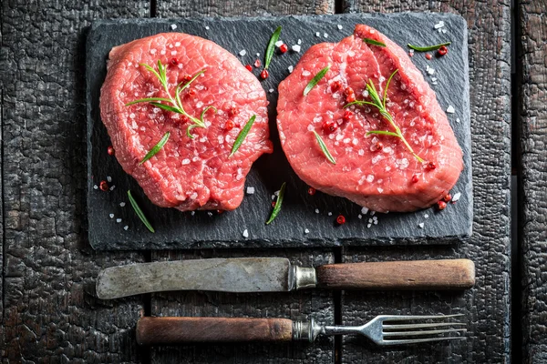 Trozo de carne de res con hierbas frescas en un plato de piedra — Foto de Stock