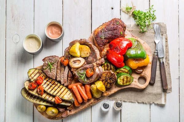 Жареный стейк и овощи с солью на деревянной доске — стоковое фото