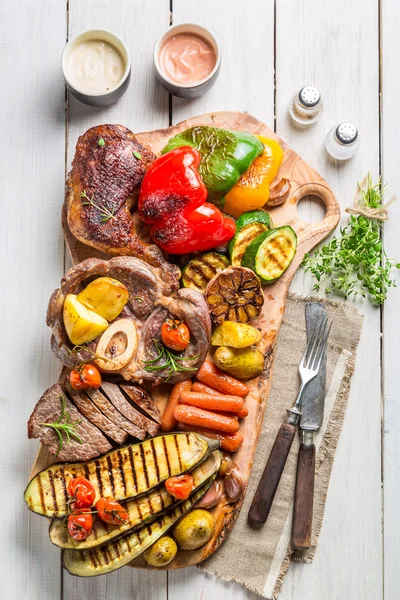 Grilled vegetables and steak with salt on wooden board — Stock Photo, Image