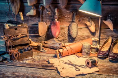 Vintage cobbler workshop with tools, shoes and leather clipart