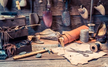 Vintage cobbler workplace with tools, leather and shoes clipart