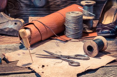 Old shoemaker workshop with tools, shoes and laces clipart