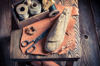 Small cobbler workshop with tools, leather and shoes clipart