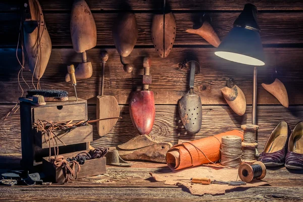 Vintage cobbler workshop with tools, shoes and laces — Stock Photo, Image