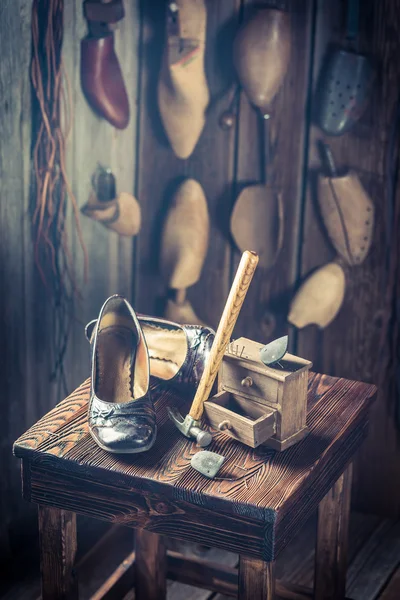 Старое рабочее место сапожника с инструментами, обувью и кожей — стоковое фото