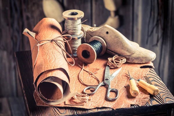 Aged cobbler workplace with tools, shoes and laces — Stock Photo, Image