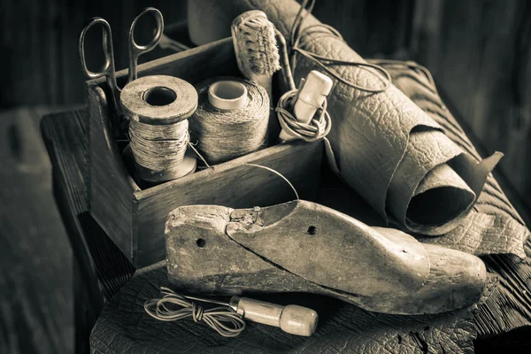 Piccolo calzolaio da lavoro con attrezzi, scarpe e lacci — Foto Stock