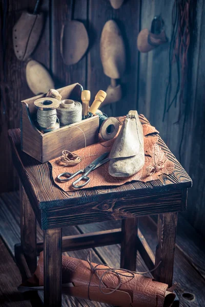 Kleine Schusterwerkstatt mit Schuhen, Schnürsenkeln und Werkzeug — Stockfoto