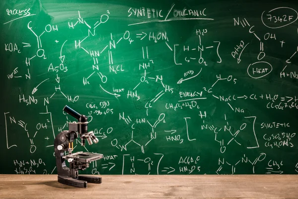 Microscope, blackboard with chemical formulas — Stock Photo, Image