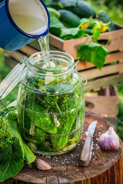 Pouring salted water into jar with cucumbers — Stock Photo, Image