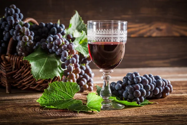 Vinho tinto saboroso com uvas em cesta de vime — Fotografia de Stock