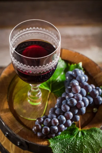 Vinho saboroso em vidro com uvas em barril de madeira — Fotografia de Stock