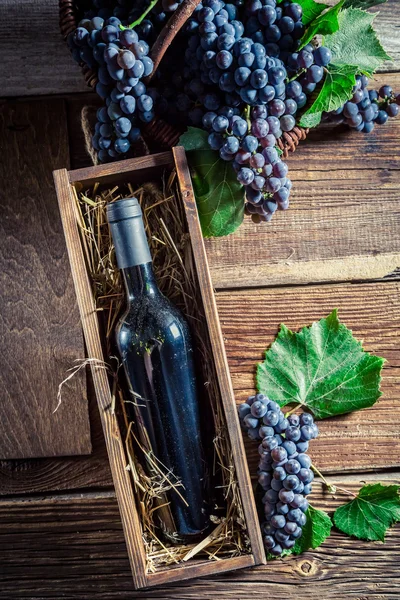 Red wine in bottle in old wooden box — Stock Photo, Image