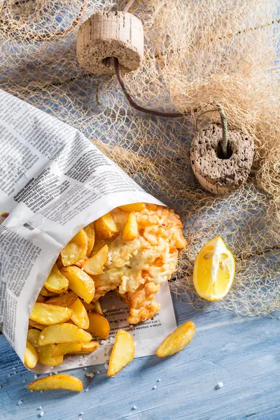 Deliziosi fish and chips serviti in carta sulla rete da pesca — Foto Stock