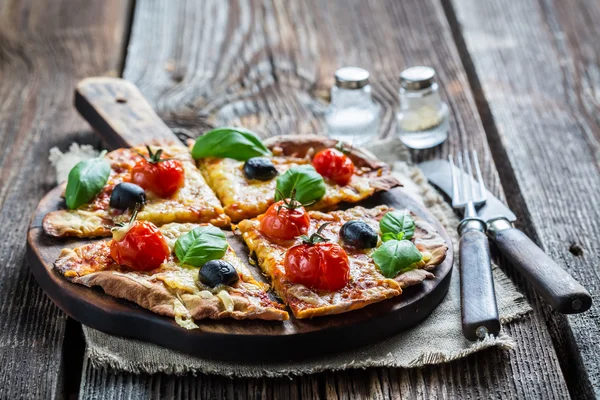 Closeup of homemade thin pizza with tomatoes and olives — Stock Photo, Image