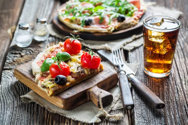 Dunne pizza gemaakt van ham, olijven, rucola en koud drankje — Stockfoto