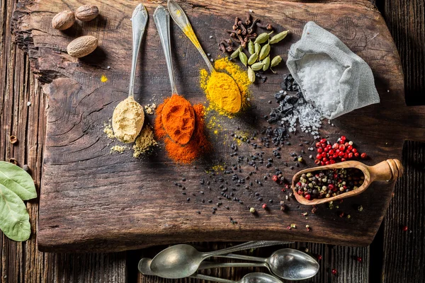 Fresh spices on spoon and herbs on old table — Stock Photo, Image