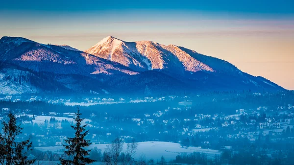 Mglisty Zakopane i oświetlone szczyt o świcie w zimie, Tatry, Polska — Zdjęcie stockowe