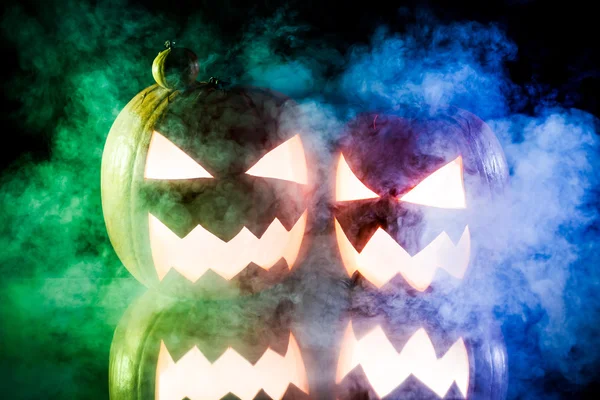 Zwei Kürbisse zu Halloween auf blauem und grünem Rauch — Stockfoto