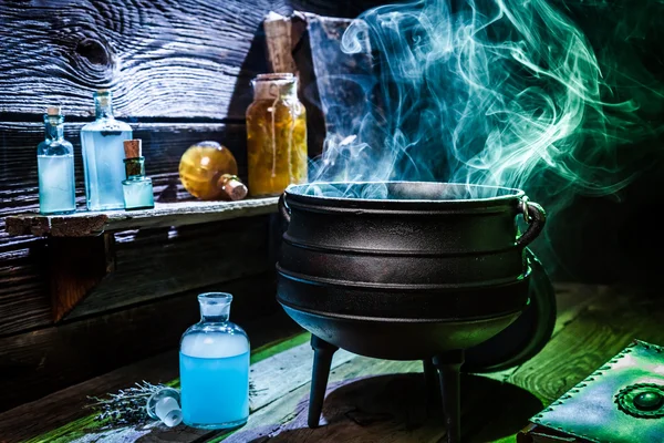Vintage witcher cauldron with blue smoke and potions for Halloween — Stock Photo, Image