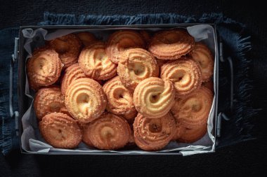 Homemade danish cookies in an old metal box on dark table clipart