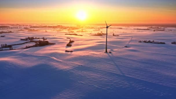 Campo nevado e turbina eólica no nascer do sol de inverno. Energia alternativa — Vídeo de Stock