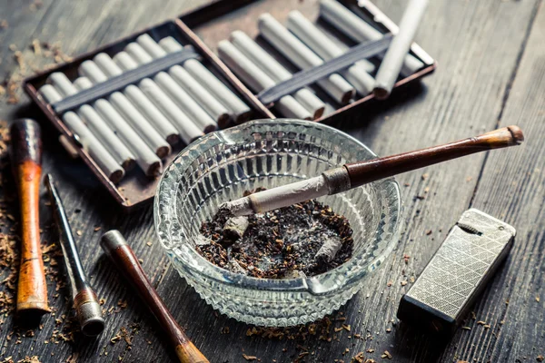 Glass ashtray with thin wooden pipes, cigarettes and lighter aro — Stock Photo, Image